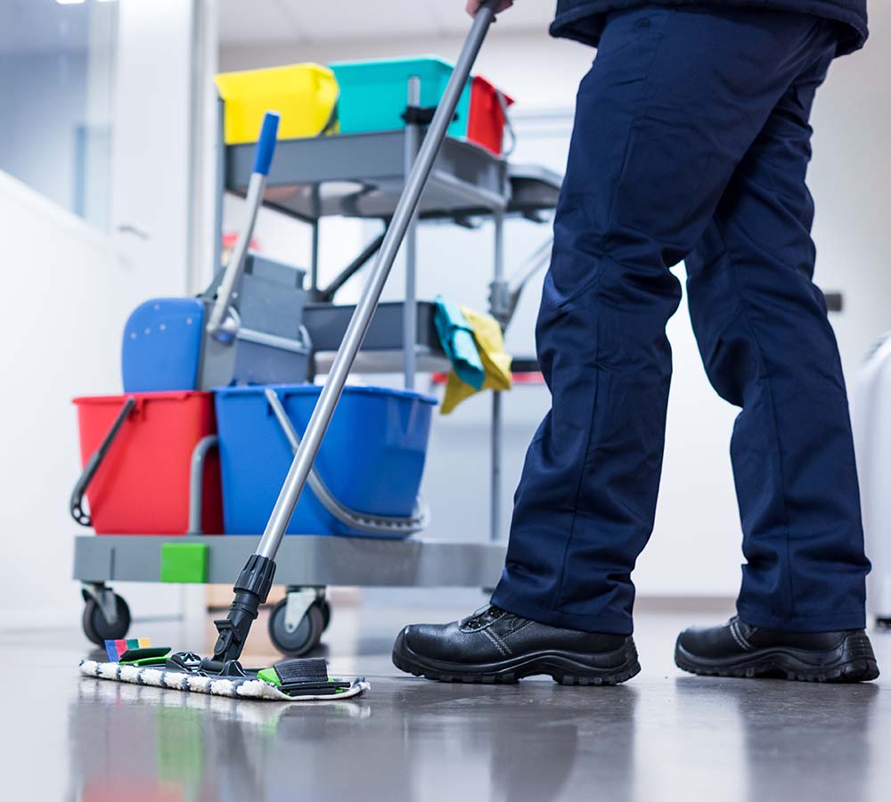 Person mit Putzausrüstung wie Wischern und Eimern im Wagen